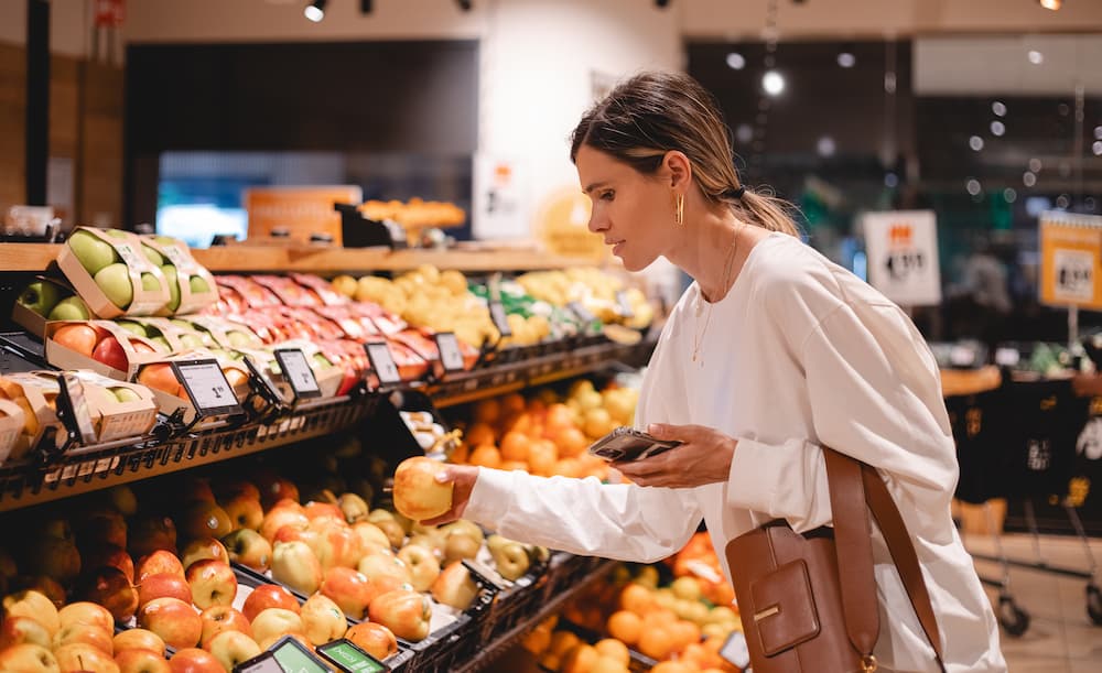 A customer selecting fresh organic produce at an Earth Fare grocery store in Virginia, representing healthy shopping options.
